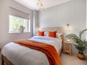 a bedroom with a large bed with orange pillows at Ty Mor in Abersoch