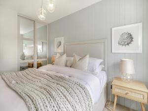 a bedroom with a large white bed and a mirror at Ty Mor in Abersoch