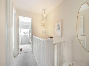 a hallway with a mirror and a white staircase at Ty Mor in Abersoch +12 photos