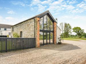 a brick house with glass doors on a gravel driveway at Whitehill Barn - Uk47195 in Kirkcambeck