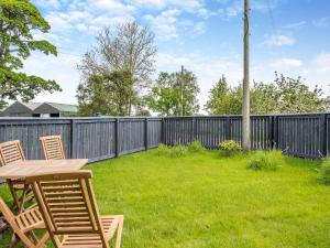 a backyard with a wooden table and chairs and a fence at Whitehill Barn - Uk47195 in Kirkcambeck
