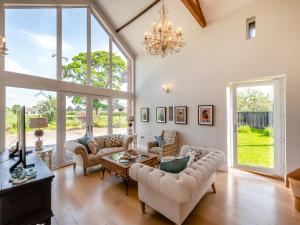 a living room with a chandelier and large windows at Whitehill Barn - Uk47195 in Kirkcambeck +12 photos