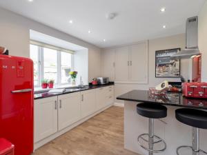 a kitchen with white cabinets and a red refrigerator at The Barn At Grislow Field in Curbar