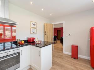 a kitchen with white cabinets and a red refrigerator at The Barn At Grislow Field in Curbar +9 photos