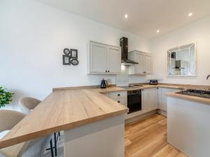 a kitchen with white cabinets and a wooden counter top at Bolton Farm in Durham +8 photos