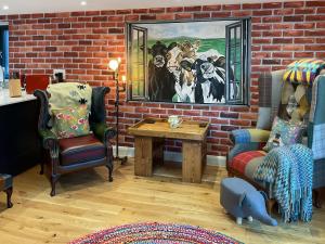 a living room with a brick wall and a table at Carreg Gwenlais Barn in Carmel
