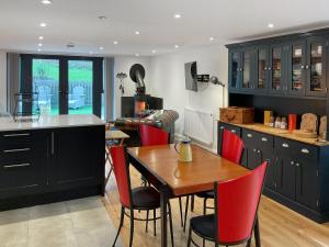 a kitchen with a wooden table and red chairs at Carreg Gwenlais Barn in Carmel +14 photos