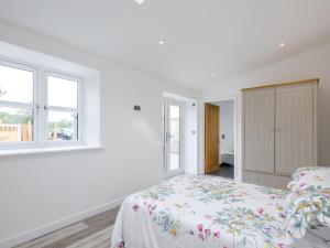 a white bedroom with a bed and two windows at Marshall Cottage in Santon