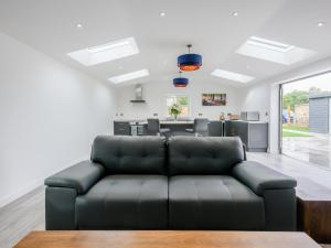 a living room with a black leather couch at Marshall Cottage in Santon