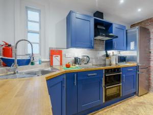 a kitchen with blue cabinets and a sink at Ystwyth House in Borth