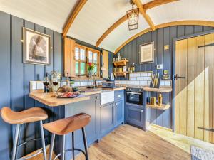 a kitchen with blue walls and a counter with stools at Flossys Hut - Uk43675 in Haworth