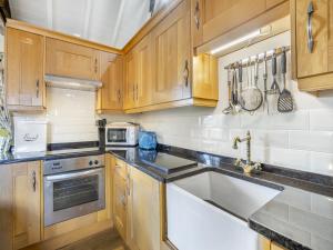 a kitchen with wooden cabinets and a sink at The Hayloft - Uk47153 in Burgh le Marsh