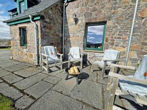 a group of chairs sitting outside of a stone building at Rubha Lodge in Shieldaig