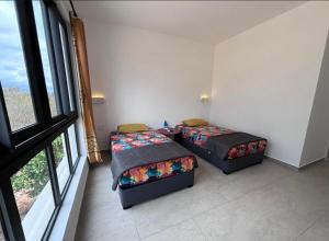 two beds in a room with a window at J'Vais Residence in Flic-en-Flac