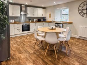a kitchen with a wooden table and white chairs at Darris Farmhouse in Lochend