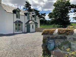 a white house with a stone wall in front of it at Darris Farmhouse in Lochend +6 photos