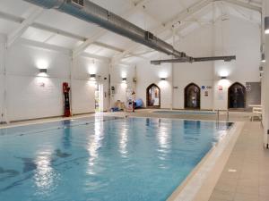 an indoor swimming pool with blue water in a building at The Parade Apartment in Reighton