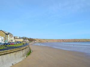 a beach with cars parked next to the water at The Parade Apartment in Reighton +1 photo