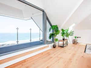 an empty living room with large windows and plants at The Penthouse in Woolacombe