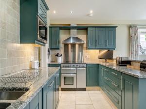 a kitchen with blue cabinets and marble counter tops at Coach House - Uk49887 in Preston