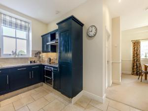 a kitchen with black cabinets and a clock on a wall at Longlands - Uk49289 in Preston