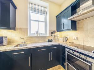 a kitchen with black cabinets and a sink and a window at Longlands - Uk49289 in Preston +19 photos