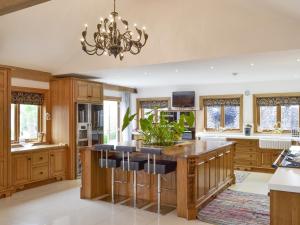 a kitchen with wooden cabinets and a large island with bar stools at Carr End Barn A in Preesall