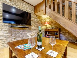 two wine glasses sitting on a wooden table with a wine bottle at Kilcot Coach House in Hillsley