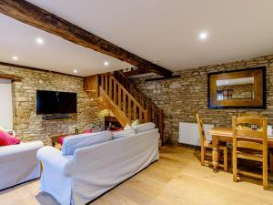 a living room with white furniture and a stone wall at Kilcot Coach House in Hillsley