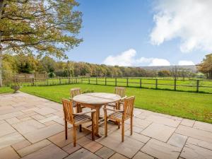 a table and chairs on a patio with a view of a field at Windover Barn in Horsham