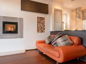 an orange leather couch in a living room with a fireplace at Orrest Howe in Windermere