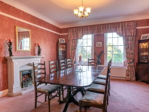 a dining room with a table and chairs and a fireplace at Orrest Howe in Windermere