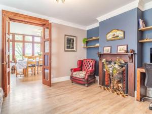 a living room with a fireplace and a red chair at Riversdelle in Beccles