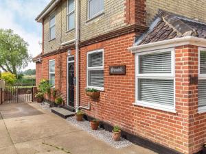 a brick house with white windows and potted plants at Riversdelle in Beccles