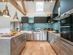 a large kitchen with stainless steel appliances and blue tiles at The Pendre Longbarn in Pentre-briwnant