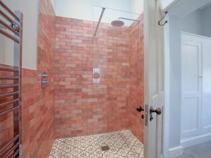a bathroom with a shower with a brick wall at The Pink House in Branscombe