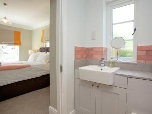 a white bathroom with a sink and a bed at The Pink House in Branscombe