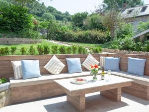 a bench on a patio with pillows and a table at The Pink House in Branscombe