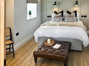 a bedroom with a large bed with a brown leather stool at Ty Twm in Criccieth