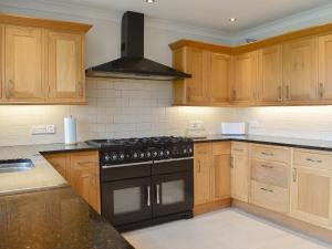 a kitchen with wooden cabinets and a stove top oven at Llwyn Ysgaw in Cemaes Bay +34 photos