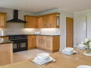 a kitchen with wooden cabinets and a table with bowls on it at Llwyn Ysgaw in Cemaes Bay