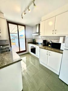 a kitchen with white appliances and a large window at Penthouse Seven Oceans Moraira in Moraira