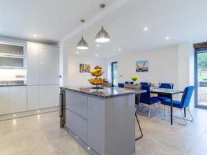 a kitchen with white cabinets and a table with blue chairs at Skylark Barn-Uk31354 in Swaffham