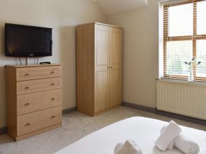 a bedroom with a tv and a bed and a dresser at Ty Fynnon Cottage-Uk2786 in Penmaen-mawr