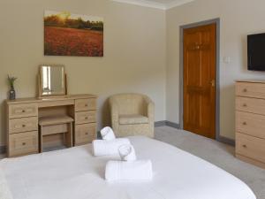 a bedroom with a white bed with a desk and a chair at Ty Fynnon Cottage-Uk2786 in Penmaen-mawr
