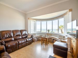 a living room with a leather couch and a table at Waterside in Llandrillo-yn-Rhôs