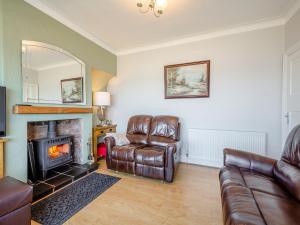 a living room with a couch and a fireplace at Waterside in Llandrillo-yn-Rhôs