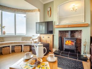 a living room with a fireplace and a table at Waterside in Llandrillo-yn-Rhôs