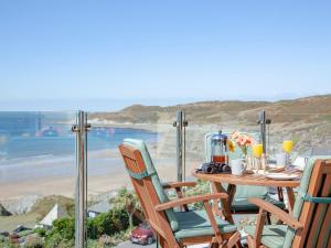 a table with chairs and a view of a beach at Soft Sands - Cottage in Woolacombe