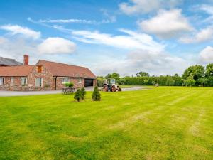 a large yard with a house and a tractor at The Stables in Cheddar